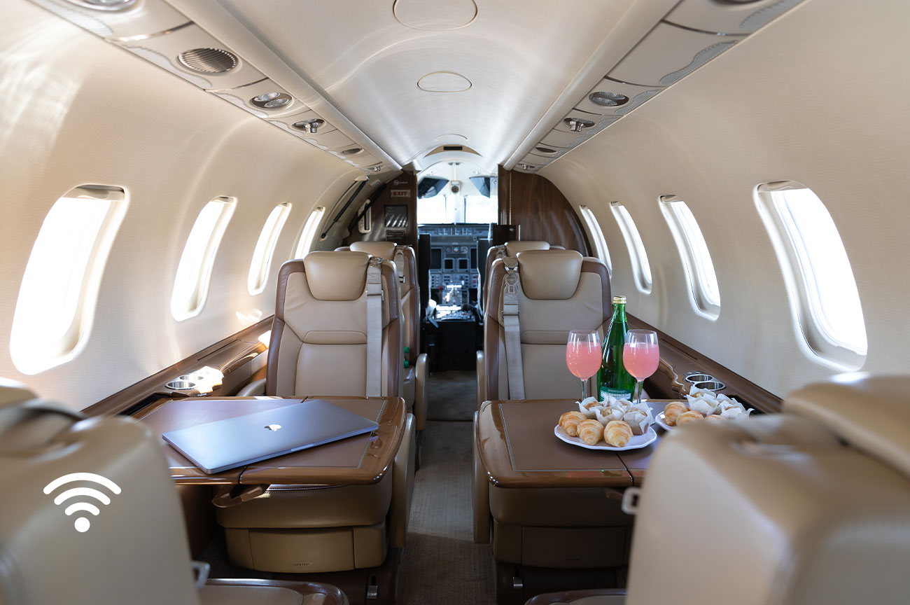 Image of the International Air Charter Learjet 45 interior looking toward cabin with refreshments and laptop displayed; plane is wifi enabled.