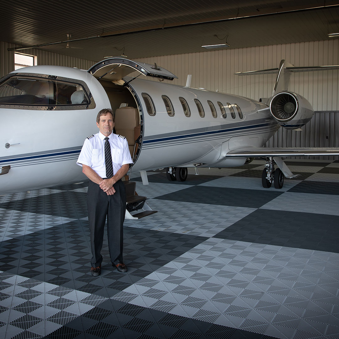 Image of pilot Dan Sauer standing by Learjet to welcome you to private charter flights with International Air Charters.